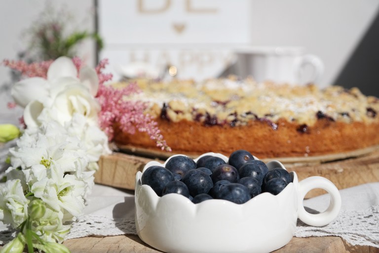 Schale mit Heidelbeeren und Kuchen im Hintergrund